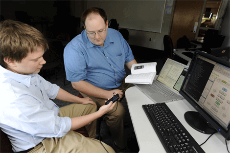 From left, Western Carolina University student Chris Blades and assistant professor Andrew R. Dalton work together to design a class in which WCU students will write programs for mobile phone applications and test them on Motorola Droid phones.